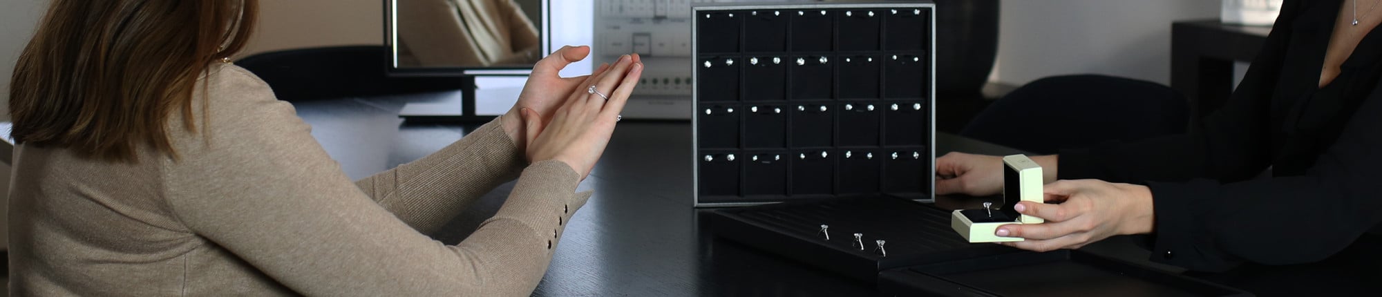 Beratungsszene mit Diamantringen in schwarzen Präsentationsboxen auf einem Tisch