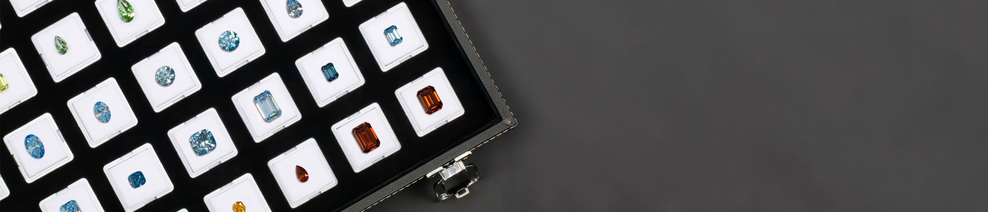 Offene Schmuckbox mit farbigen Diamanten in Weiß, Blau, Grün und Orange, einzeln präsentiert