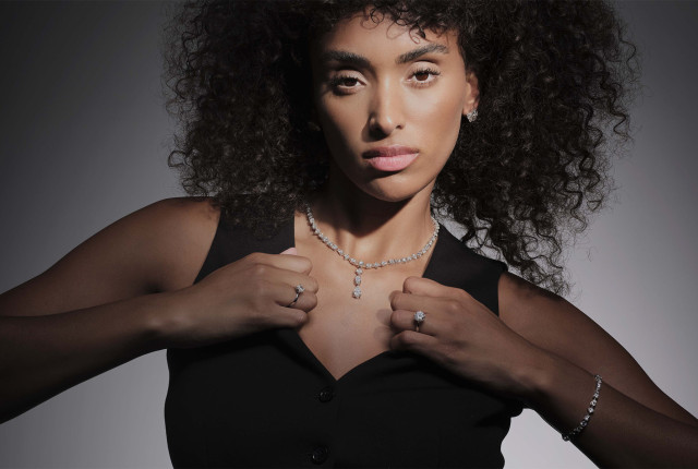 Woman wearing a diamond tennis necklace with a teardrop pendant, matching ring and bracelet