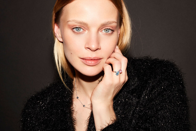 Woman wearing a rose gold toi et moi ring with two colored gemstones and a small diamond accent