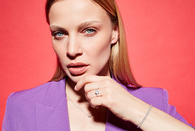 Mujer con pulsera de diamantes y anillo de oro blanco con diamante, sobre blazer lila