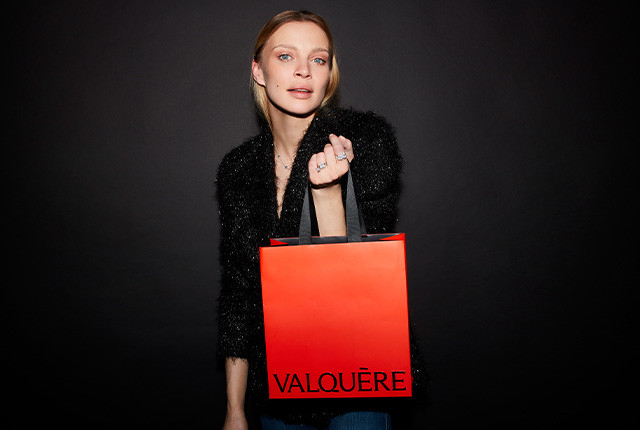Femme portant une bague sertie de diamants et un sac rouge Valquère en boutique