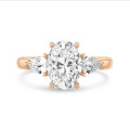 Bague trilogie en or rouge avec un diamant ovale de 3.00 carats et deux diamants en forme de poire de 0.35 carat chacun.
