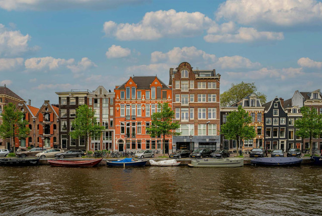 Vue des maisons de canal à Amsterdam, façades historiques colorées au bord de l’eau