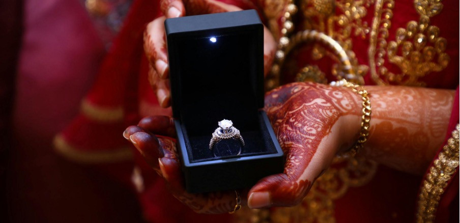 Indische Frau, die einen Diamant-Verlobungsring in einer Samtschachtel präsentiert